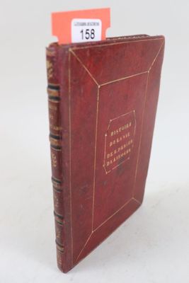 un vieux livre à la couverture rouge posé sur une table blanche