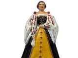 figurine représentant une femme vêtue d'une robe noire et blanche ornée d'une bordure dorée