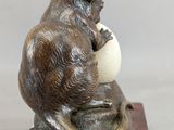 statue of a mouse sitting on a ball on a wooden base
