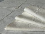 three folded napkins sitting on a table with a monogramed design
