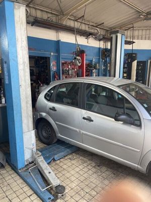 une voiture argentée posée sur un pont élévateur dans un garage