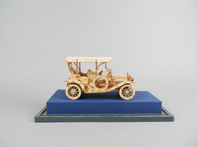 maquette en bois d'une voiture ancienne exposée sur un socle bleu