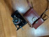 a camera and a brown bag on a wooden floor