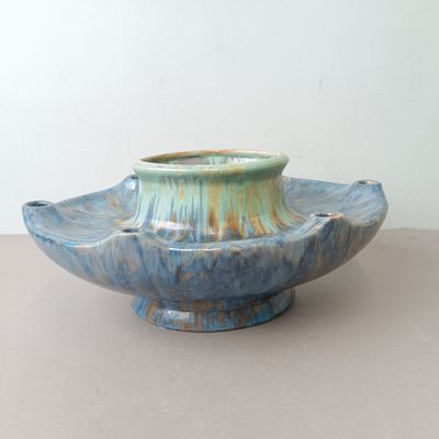 un vase bleu posé sur une table avec un mur blanc en arrière-plan