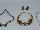 Trois colliers, un bracelet et un collier de perles sont posés sur une table