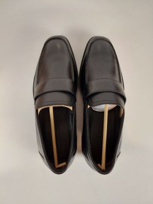 mocassins en cuir noir avec des boucles dorées sur fond blanc