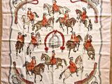 a white scarf with a picture of people riding horses on it