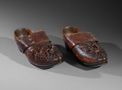 pair of wooden clogs with carvings on them on a gray surface