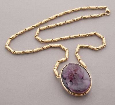 a close up of a necklace with a purple stone on a gold chain