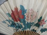 a fan with flowers painted on it sitting on a table
