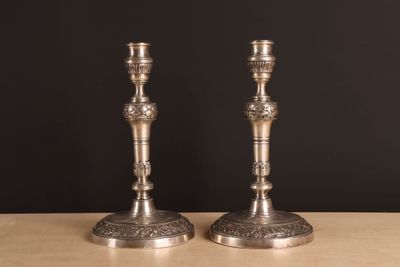 une paire de bougeoirs en argent posés sur une table, sur fond noir