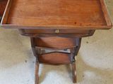 an old wooden table with a drawer underneath it on a carpeted floor