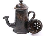 a black tea pot with a tea strainer on it