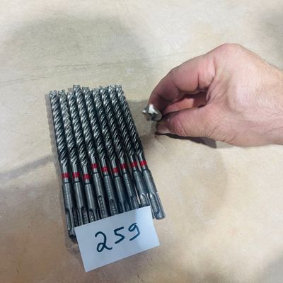 a person holding a bunch of drill bits in their hand
