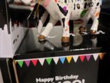 une figurine de vache sur laquelle est inscrit « Joyeux anniversaire, meuh ! »