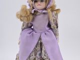 doll with blonde hair wearing a purple dress and hat