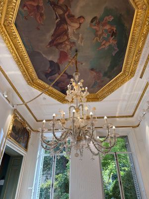 un lustre au milieu d'une pièce dont le plafond est orné d'une peinture