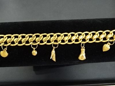 un gros plan d'un bracelet à chaîne en or orné de breloques