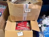 Plusieurs cartons de fournitures sont empilés les uns sur les autres par terre.