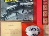 plusieurs livres posés sur une table, avec une photo d'un bus en arrière-plan