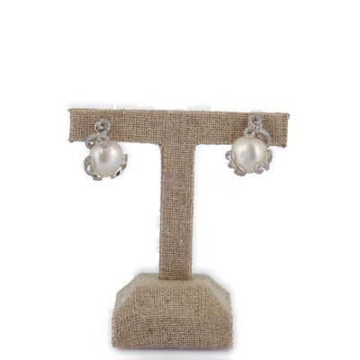 boucles d'oreilles en perles et diamants présentées sur un présentoir, sur fond blanc