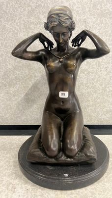 statue en bronze représentant une femme assise sur un rocher, les mains posées sur la tête