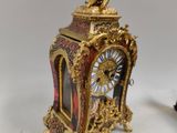 a small clock with a statue on top of it