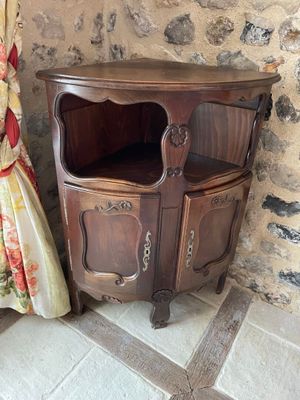 a corner cabinet next to a curtain in a room