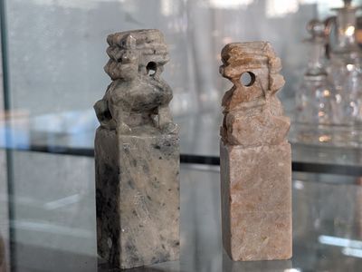 two stone figurines on display in a glass case
