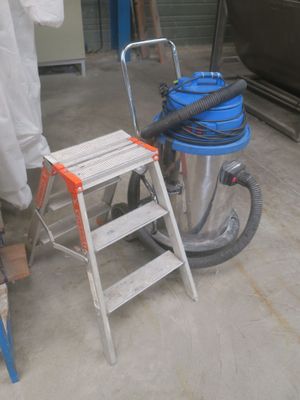 a man standing next to a vacuum and a chair