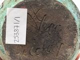 a hand holding a green vase with a label on it