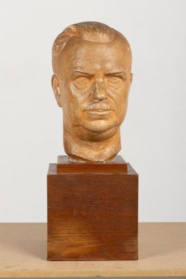 une photo d'une sculpture représentant une tête d'homme posée sur un socle en bois