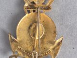 an image of a gold pin with a sword and cross on it