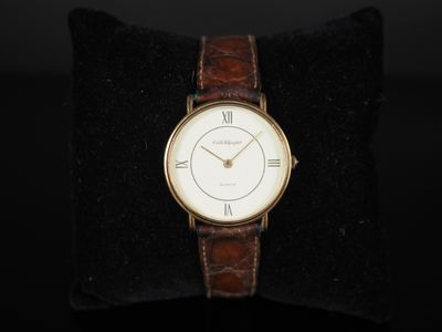 un gros plan d'une montre-bracelet posée sur un oreiller, sur une surface noire