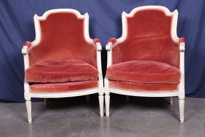 pair of red velvet chairs with white trim and wood legs