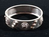 silver ring with skulls and skulls on it sitting on a black surface