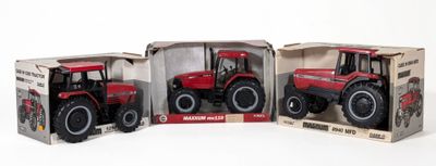 three red toy tractors in boxes on a white surface