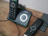 two remotes sitting on a table next to a cell phone