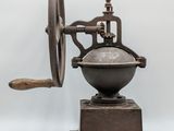 an old coffee grinder with a wooden handle on a white background