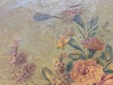 un tableau accroché au mur d'une pièce, représentant des fleurs et une libellule