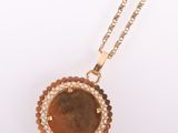 a close up of a necklace with a coin on a chain