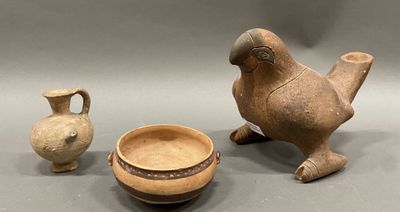 two old pottery items sitting on a gray surface next to each other