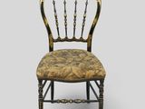 a black and gold chair with floral upholstered seat