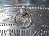 a silver vase that has a lion head on it