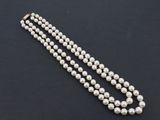 gros plan d'un collier de perles blanches sur une surface noire