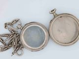 a silver pocket watch with a chain around it