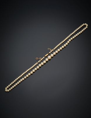 un collier de perles avec un fermoir en or sur fond noir