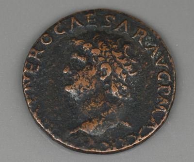 une vieille pièce de monnaie sur laquelle figure un homme assis sur une table