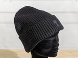 black knitted beanie on a mannequin head on a wooden table