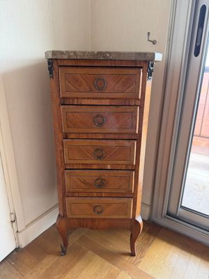 une haute commode en bois dans le coin d'une pièce